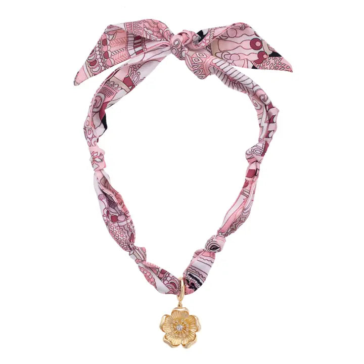 Pink patterned headband with a gold pendant on a white background